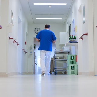 Ein Krankenpfleger geht über einen Krankenhausflur. 