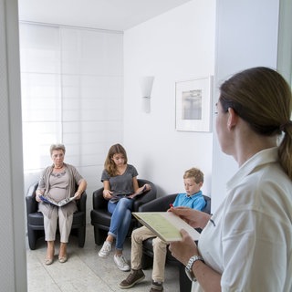 Wartezimmer einer Arztpraxis, Sprechstundenhilfe und Patienten. Geschäftsmodell Gesundheit: Warum Investoren Arztpraxen kaufen und zu MVZ umwandeln