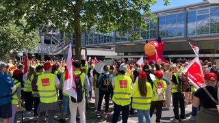 Beschäftigte des Uniklinikums Freiburg streiken in ver.di-Westen vor dem Klinikgebäude.
