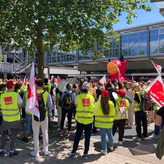 Beschäftigte des Uniklinikums Freiburg streiken in ver.di-Westen vor dem Klinikgebäude.