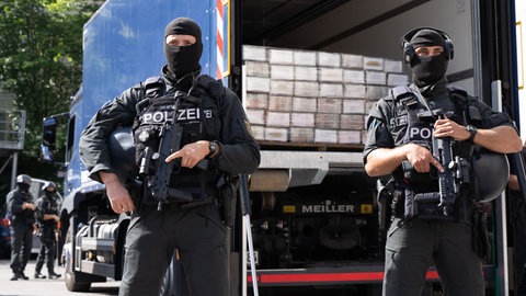 Polizisten sichern einen Polizei-Lastwagen mit sichergestelltem Kokain auf der Ladefläche.