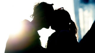 Ein junges Paar küsst sich im Licht des Sonnenuntergangs.