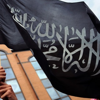  Ein Muslim hält eine islamische Fahne mit dem Glaubensbekenntnis, der sogenannten Schahada in die Höhe (Symbolbild)