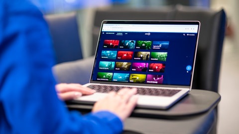 Eine Person sitzt vor einem Laptop, auf dem die ARD-Mediathek angezeigt wird