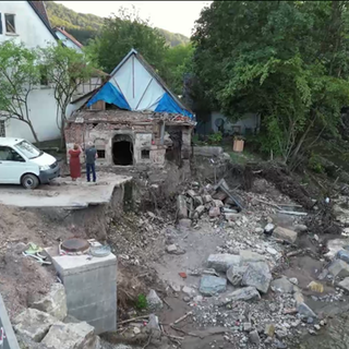 Pärchen steht vor zerstörtem Haus