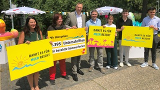 Beim GEW-Protest werden Plakate gegen die Sommerferien-Arbeitslosigkeit von Lehrkräften im Referendariat hochgehalten.