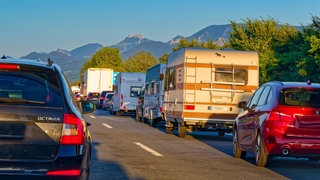 Autos stehen im Stau auf der A8, im Hintergrund sind Berge zu sehen