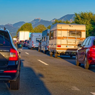 Autos stehen im Stau auf der A8, im Hintergrund sind Berge zu sehen