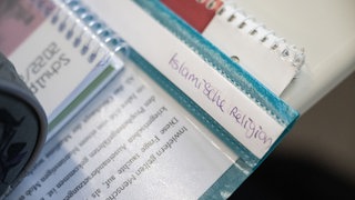 Ein Hefter mit der Aufschrift "Islamische Religion" liegt auf einem Schultisch.