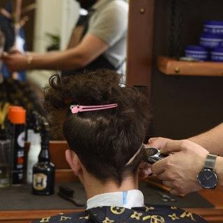 In einem Barbershop werden einem Kunden die Haare geschnitten.