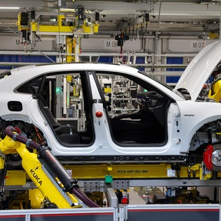 Industrieroboter arbeiten an einem vollelektrischen Porsche Macan nach der Hochzeit (der Verbindung von Fahrwerk und Motor mit der Karosse) im Werk Leipzig. Die Auslastung der Automobilhersteller-Werke war 2023 in Deutschland deutlich zurückgegangen.