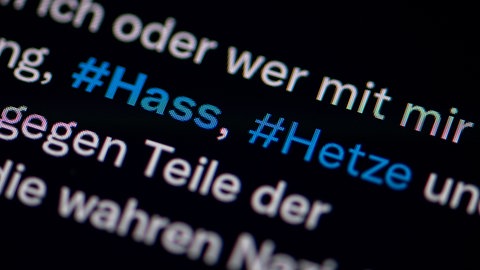 Auf dem Bildschirm eines Smartphones sieht man die Hashtags Hass und Hetze in einem Twitter-Post (Symbolbild).