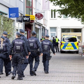 Einsatzkräfte der Polizei gehen am Mittag am Tatort vorbei. Bei einer Attacke auf der 650-Jahr-Feier der Stadt Solingen am 23.08.2024 hat es drei Todesopfer und mehrere Verletzte gegeben.