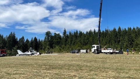 Auf einem Feld am Waldrand bei Böttingen (Kreis Tuttlingen) sind die Feuerwehr und ein Kran bei der Bergung eines abgestürzten Kleinflugzeugs. 