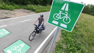 Ein Radler fährt auf einem Radschnellweg an einem Verkehrsschild vorbei.