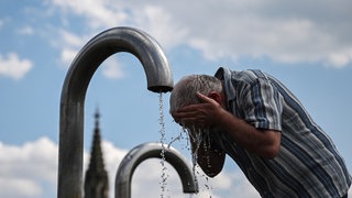 Ein Passant kühlt sich an einem Mineralwasserbrunnen in Stuttgart ab. Laut dem Deutschen Wetterdienst war der Sommer 2024 in Baden-Württemberg zu heiß.