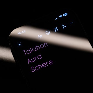 Die drei Worte "Talahon", "Aura" und "Schere" sind auf dem Display eines Smartphones zu sehen.