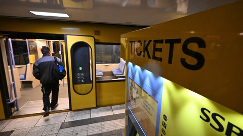 Neben einem Ticketschalter steigt ein Mann in einen Zug der Stuttgarter Stadtbahn. 
