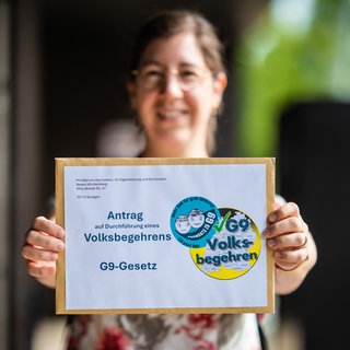 Marita Raschke, Vertreterin der Elterninitiative "G9 jetzt!", hält vor dem Innenministerium einen Umschlag mit einem Antrag auf Durchführung eines Volksbegehrens bezüglich des G9-Gesetzes in ihren Händen (Archivbild).