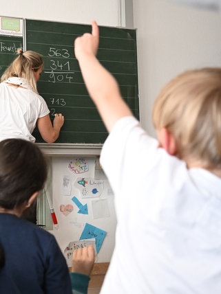 Schüler einer Grundschule arbeiten in einem Klassenzimmer an Mathematikaufgaben. 