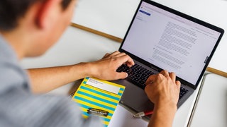 Ein Schüler eines Gymnasiums sitzt vor einem Laptop und benutzt ein KI-Tool.