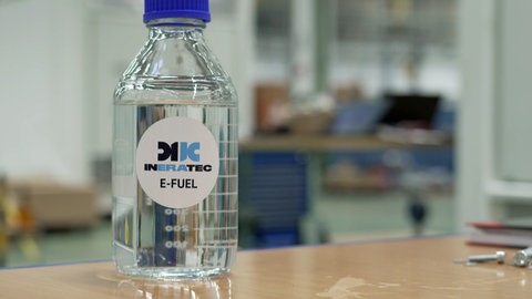 Eine Flasche mit E-Fuel von Ineratec steht auf einer Werkbank.