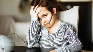 (Symbolbild) Krankes Kind trägt eine Inhalationsmaske.