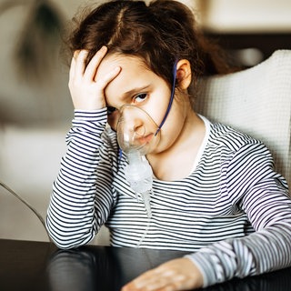(Symbolbild) Krankes Kind trägt eine Inhalationsmaske.