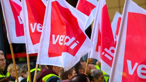 Streikende halten Flaggen der Gewerkschaft ver.di in die Luft. In Baden-Württemberg gibt es zahlreiche Warnstreiks im öffentlichen Dienst.