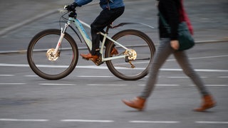 Ein E-Bike-Fahrer überholt eine Fußgängerin. Wegen des ver.di-Streiks bei Bus- und Bahn mussten am Freitag Menschen auf andere Verkehrsmittel ausweichen.