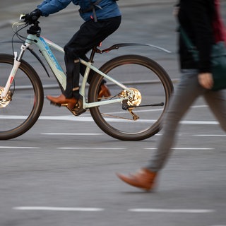 Ein E-Bike-Fahrer überholt eine Fußgängerin. Wegen des ver.di-Streiks bei Bus- und Bahn mussten am Freitag Menschen auf andere Verkehrsmittel ausweichen.
