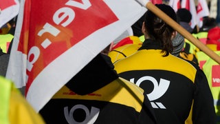Mitarbeiter der Post demonstrieren mit ver.di-Flagge. Bei DHL wird am Donnerstag in BW in der Zustellung gestreikt.