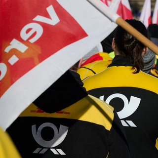 Mitarbeiter der Post demonstrieren mit ver.di-Flagge. Bei DHL wird am Donnerstag in BW in der Zustellung gestreikt.