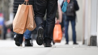 Passanten laufen mit Einkaufstüten durch eine Einkaufsstraße. Kleine Unternehmen in Baden-Württemberg sind besorgt wegen der Nachfrage im Land.