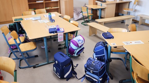 Schultaschen stehen in einem Klassenzimmer. Schulen sollen künftig mehr gegen sexualisierte Gewalt tun.