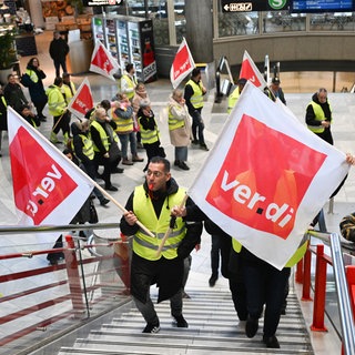 Mitglieder der Gewerkschaft ver.di gehen mit Fahnen bei einem Streik durch ein Terminal des Stuttgarter Flughafens.