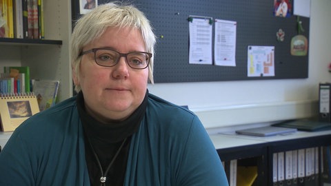 Eine Frau mit kurzen blonden Haaren und Brille sitzt in einem Büro: Auch die Rektorin der Gesamtschule in Lauda-Königshofen (Main-Tauber-Kreis), Natalie Ederer, setzt sich für eine Arbeitszeiterfassung für Lehrkräfte ein.