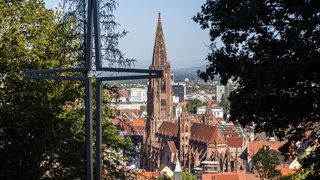 Ein stilisiertes Kreuz steht auf dem Freiburger Schlossberg während im Hintergrund das Münster zu sehen ist. Nach drei umstrittenen Personalentscheidungen wird das Erzbistum Freiburg stark kritisiert.