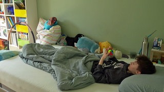 Die an Long Covid erkrankte Julie liegt in ihrem Bett im Kinderzimmer