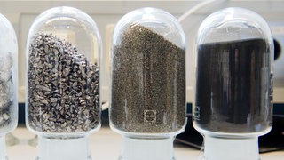 Proben von seltenen Metallen wie Wolfram in verschiedenen zerkleinerten Stufen stehen in einem Labor.