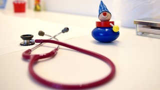 Ein Stethoskop und Kinderspielzeug liegen in einer Kinderarztpraxis auf einem Tisch.