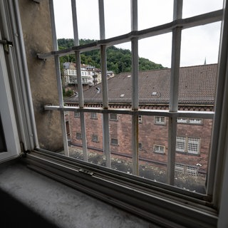 Ein Gebäude des Ex-Gefängnisses "Fauler Pelz" in der Heidelberger Altstadt ist durch ein vergittertes Fenster zu sehen. 