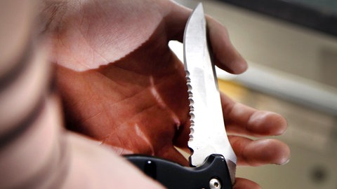 Eine Person hat ein Klappmesser in der Hand.