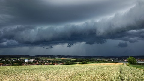 Eine Gewitterzelle mit dunklen Wolken baut sich am Himmel auf.