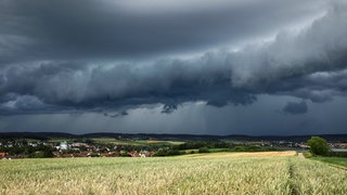 Eine Gewitterzelle mit dunklen Wolken baut sich am Himmel auf.