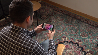 Ali schaut sich auf seinem Smartphone ein Familienfoto an.