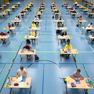Schüler und Schülerinnen sitzen während des Deutsch-Abi mit dem vorgeschriebenen Abstand zueinander in der Sporthalle des Albert-Einstein-Gymnasiums vor der Prüfung. Eine Elterninitiative startet am Samstag die Sammlung von Unterschriften für einen Volksantrag für die Rückkehr zum neunjährigen Gymnasium (G9) in Baden-Württemberg.