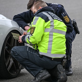 Polizisten kontrollieren ein Auto, das von einer Verkehrskontrolle am sogenannten Carfreitag herausgezogen wurde (Archivbild). 