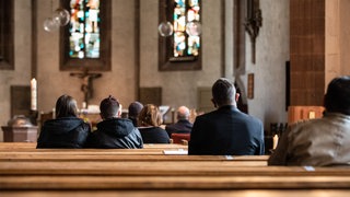 Menschen sitzen bei dem Gottesdienst in den Kirchenbänken der Leonhardskirche in Stuttgart. (Archivbild)