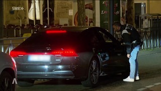 Ein Polizist kontrolliert den Fahrer eines sportlichen Wagen